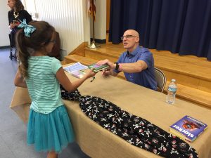 Korman signs a book for one of many students familiar with his published works